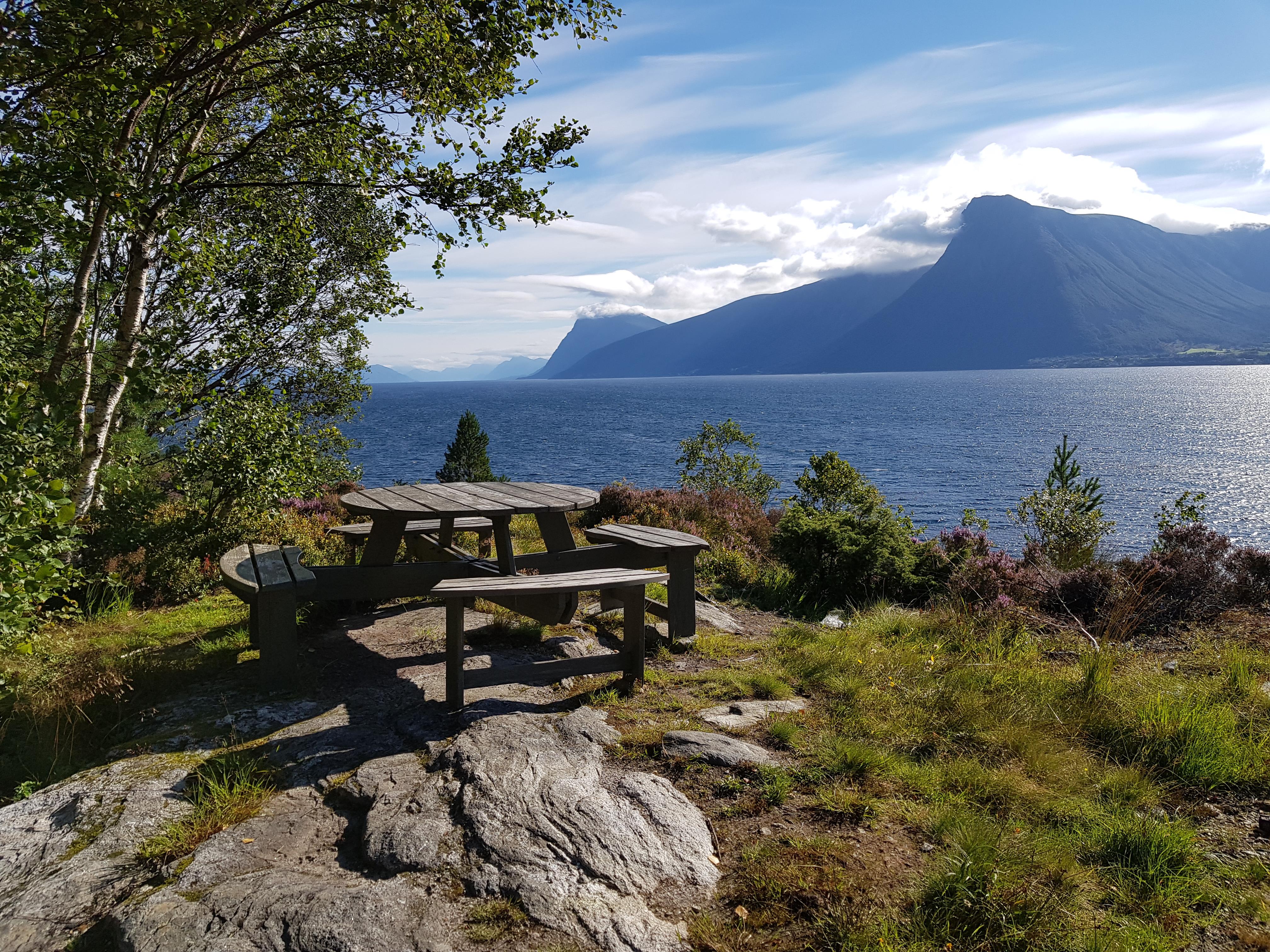 Bilete av parkbenk og bord i naturen med utsikt til fjord og fjell