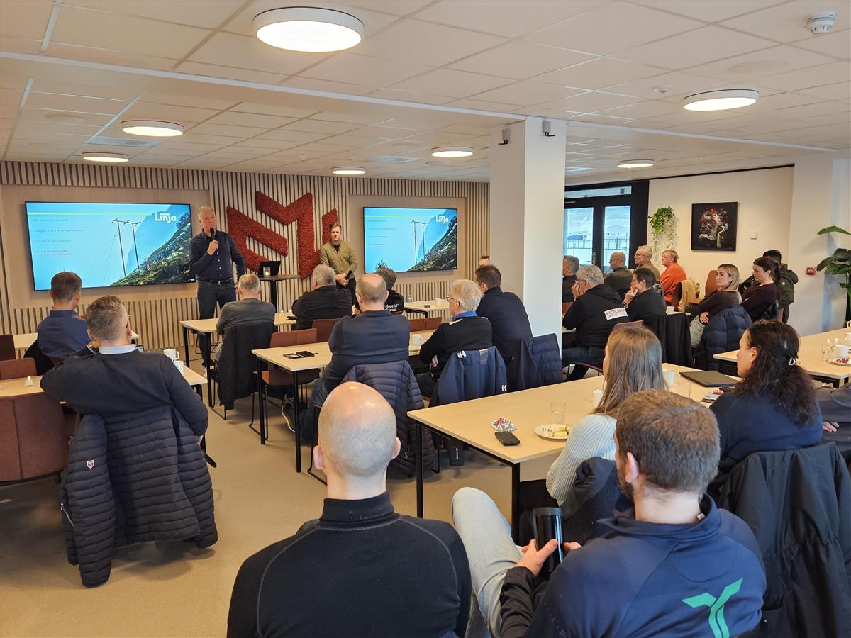 Bakerst i biletet: to personar foran ein storskjerm, vidare er ryggane til tilhøyrarane - Klikk for stort bilete