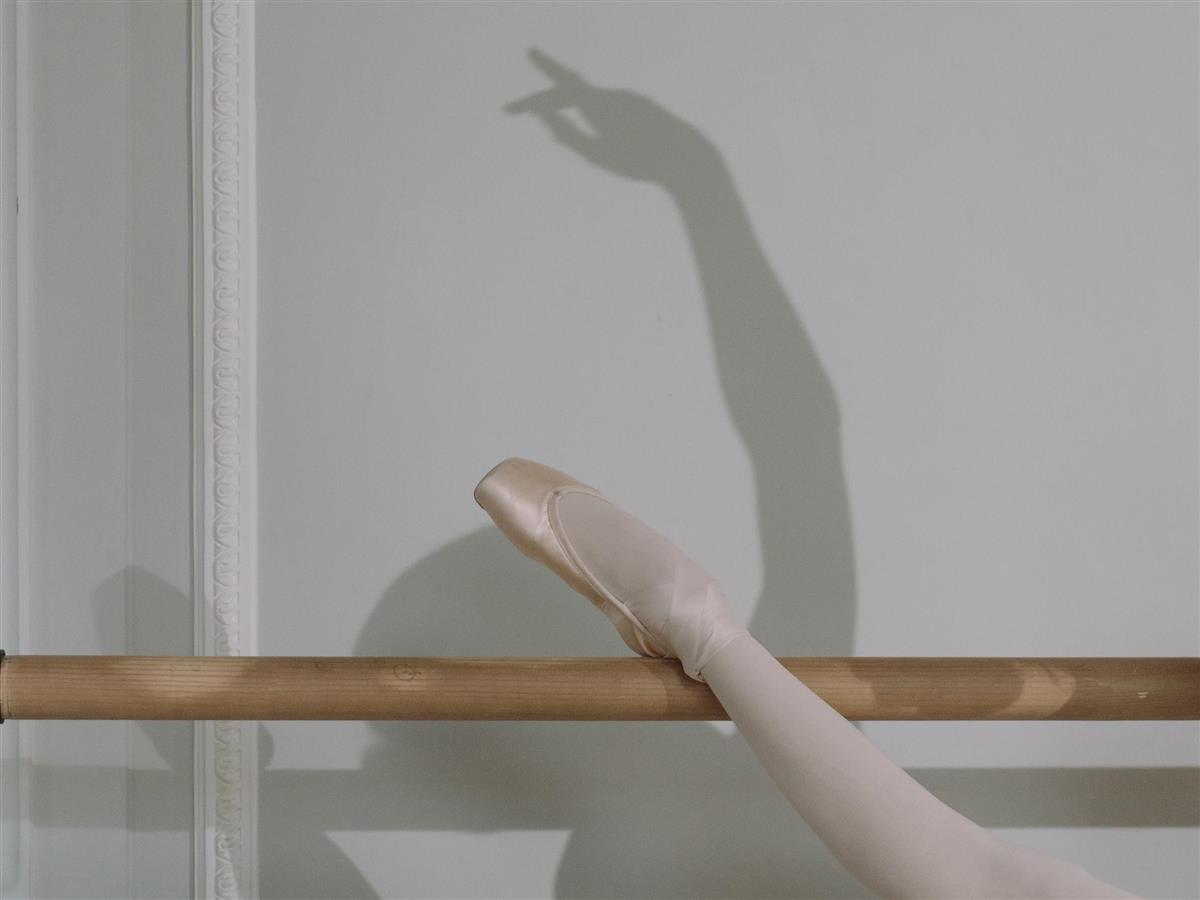 Balletdansar tøyer ut, siluett på vegg. - Klikk for stort bilete